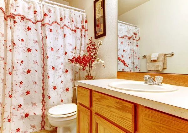Simple bedroom with flowery curtain shower and wood sink cabinet.