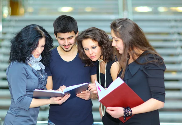 Group of students talking and holding notebooks