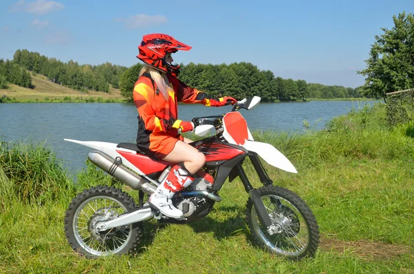 The girl sitting on a sport bike, amid lakes and forests.