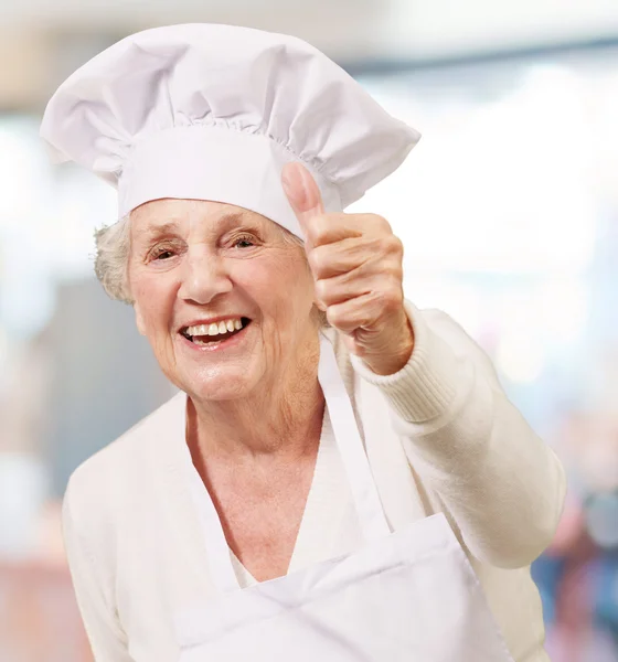 Portrait of cook senior woman doing good gesture indoor