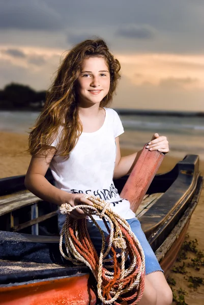 Beautiful girl sailor posing in boat at the coastline against the sunset