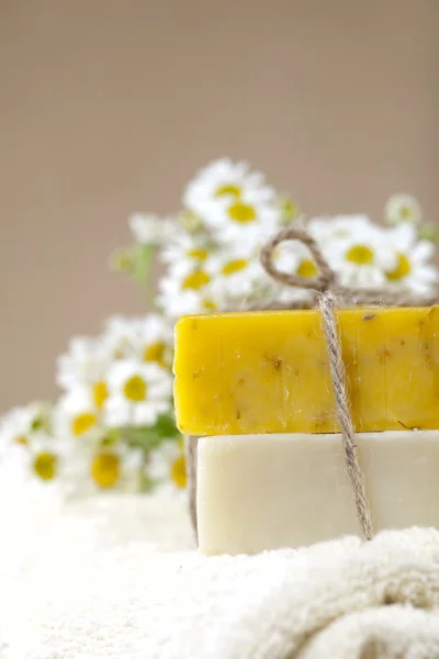 Homemade soap bars with camomile flowers and towel,