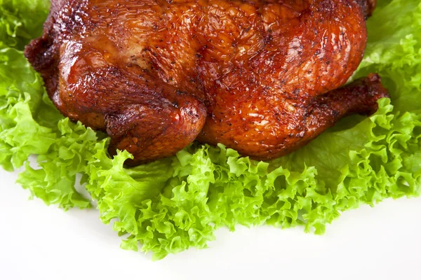 Homemade hot smoked whole chicken on leaf lettuce bed isolated o
