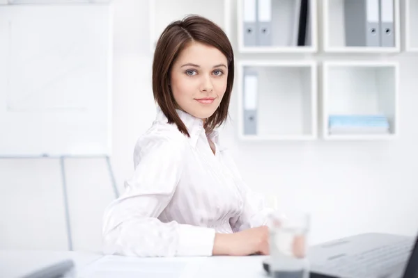 Portrait of beautiful young business woman sitting at desk at of