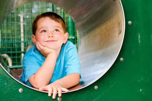 Cute young child boy or kid playing in tunnel on playground.