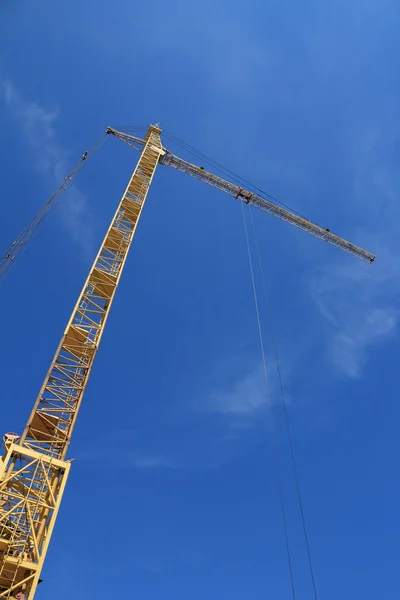 Yellow hoisting crane on blue sky background