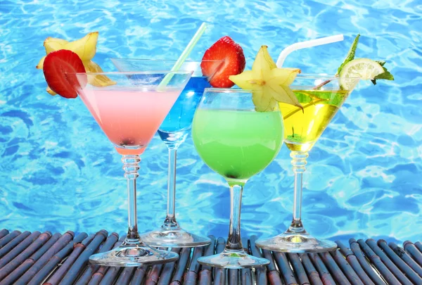 Glasses of cocktails on table on blue sea background