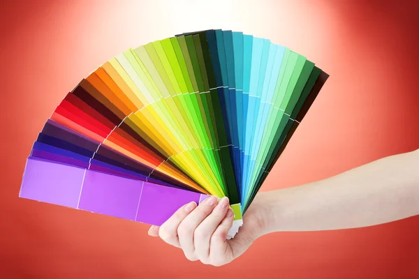 Hand holding bright palette of colors on red background