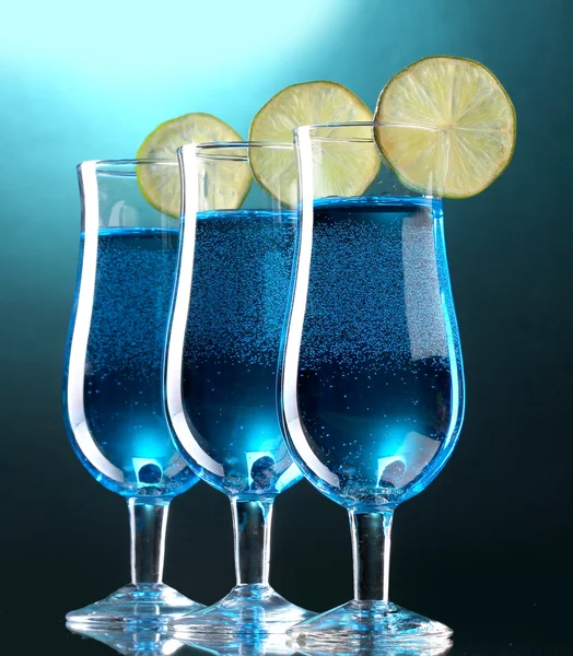 Blue cocktail in glasses with lime on blue background