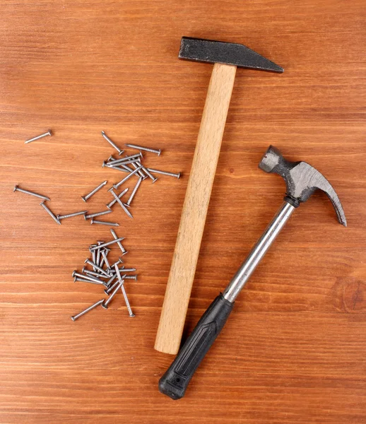 Hammers and metal nails on wooden background