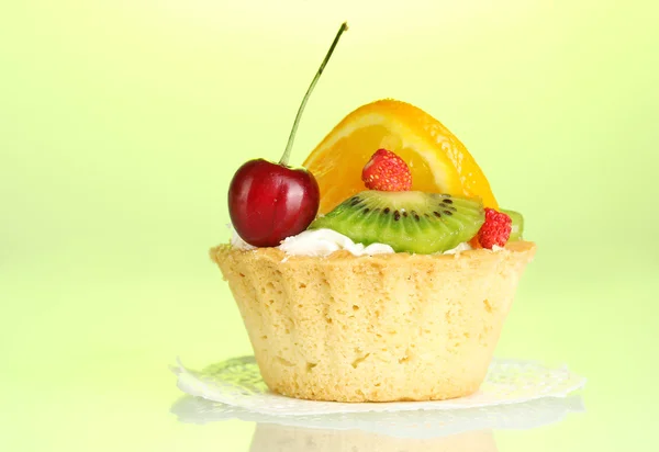 Sweet cake with fruits on green background