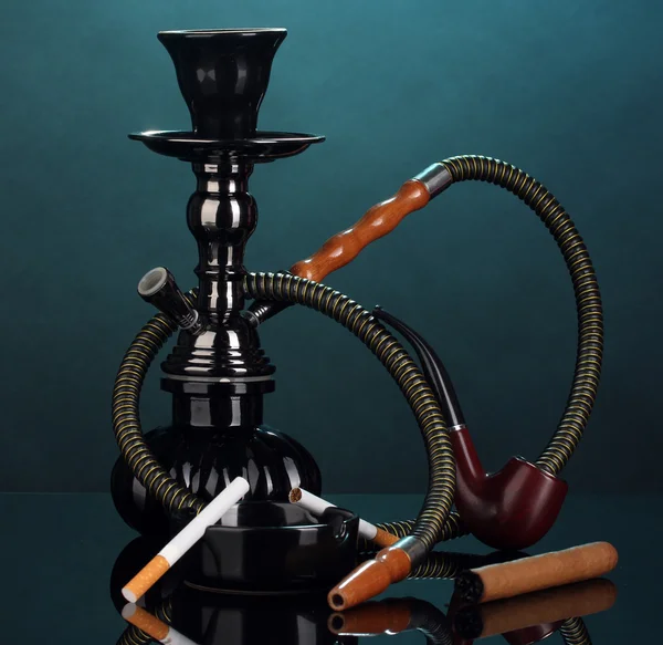 Smoking tools - a hookah, cigar, cigarette and pipe on blue background