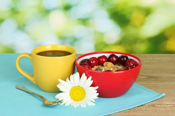 Tasty cereal with cherries for breakfast on wooden table on green background