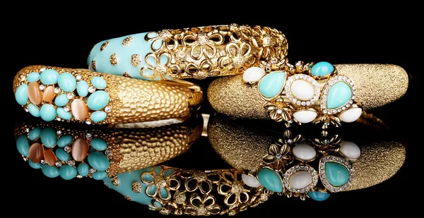 Beautiful golden bracelets with blue gems isolated on black background