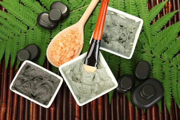 Cosmetic clay for spa treatments on bamboo background close-up