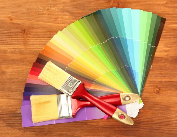 Paint brushes and bright palette of colors on wooden background