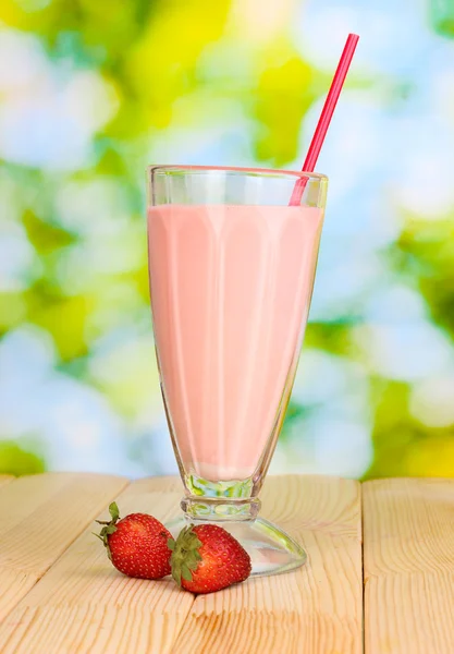 Strawberry milk shake on wooden table on bright background