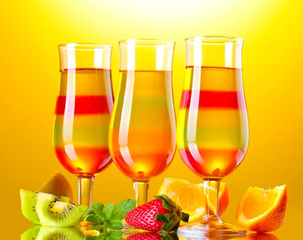 Fruit jelly in glasses and fruits on yellow background