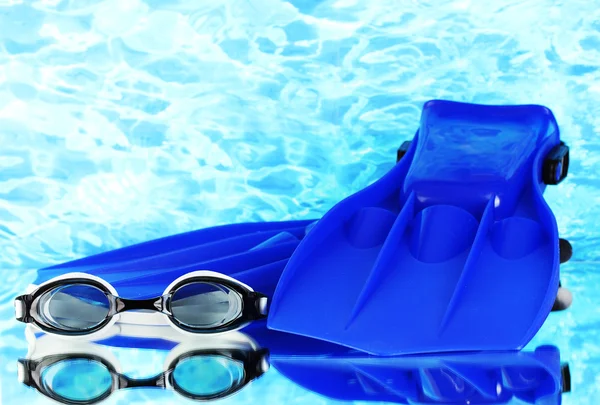 Blue flippers and goggles on blue sea background