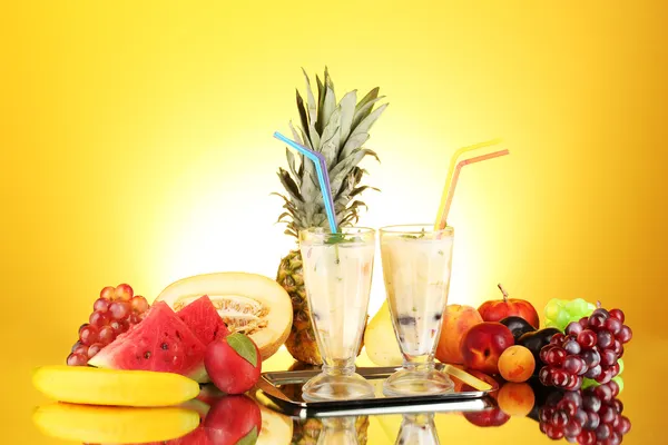 Milk shakes with fruit on yellow background close-up