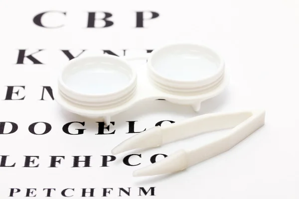 Contact lenses in containers and tweezers, , on snellen eye chart background