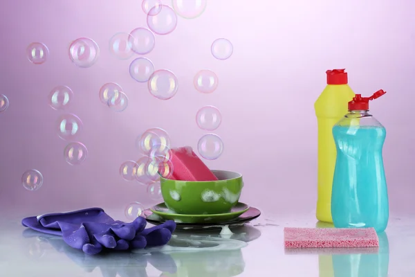 Washing dishes. Cleaning products on bright violet background