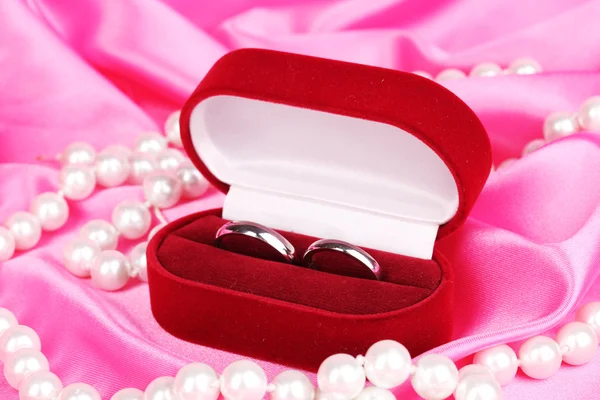 Wedding rings in red box on pink cloth background