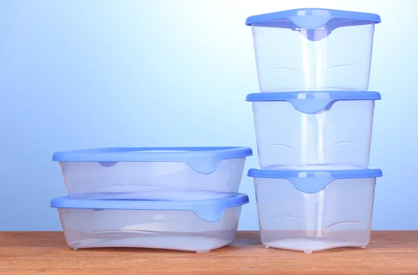 Plastic containers for food on wooden table on blue background