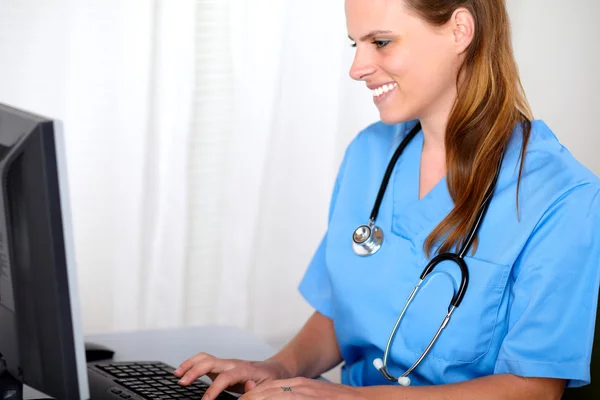 Blonde friendly young nurse looking to computer