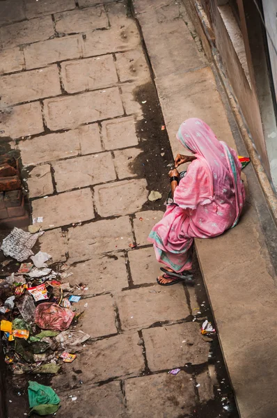 Poor woman on the dirty street, India