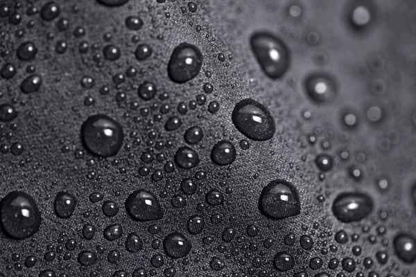 Lotus effect with water drops on black textile — Stock Photo #11799409