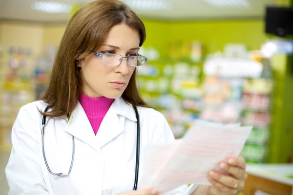 Female doctor reading prescription in pharmacy
