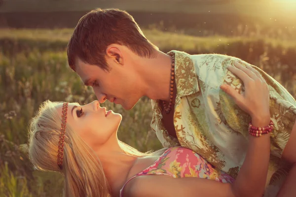 Cute young man kisses beautiful woman against sunset.