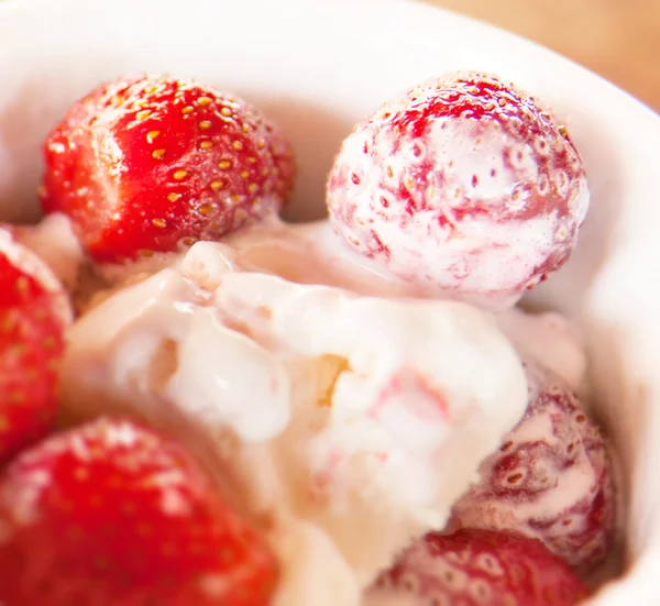 Strawberries with ice cream in a bowl on the table