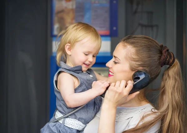 Mother and baby talking phone in city