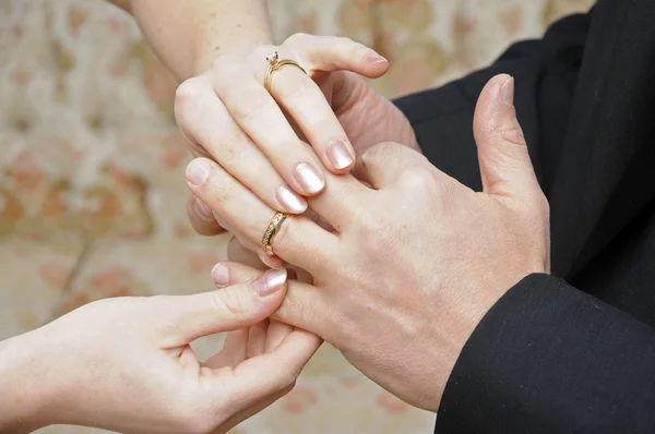 Bride placing ring on finger of Groom