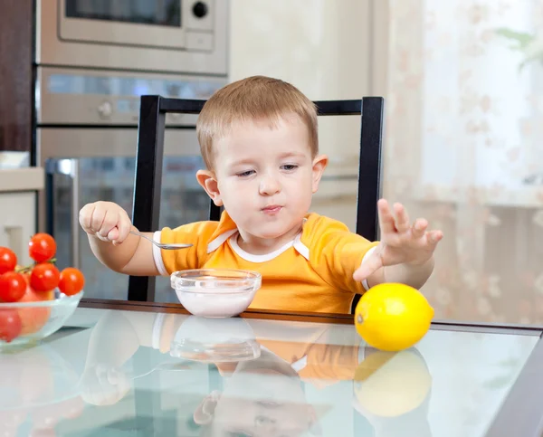 Cute little boy eating healthy food at kitchen