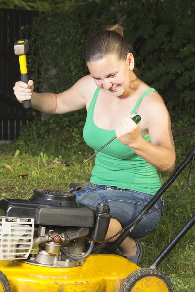 Angry girl breaking in pieces old lawn mover