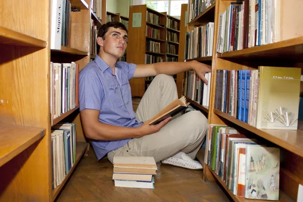 Male university student reads a book in the library