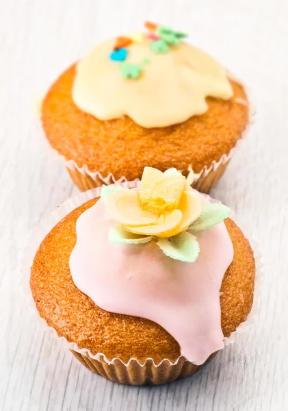 Muffins with sugar icing and edible flowers color