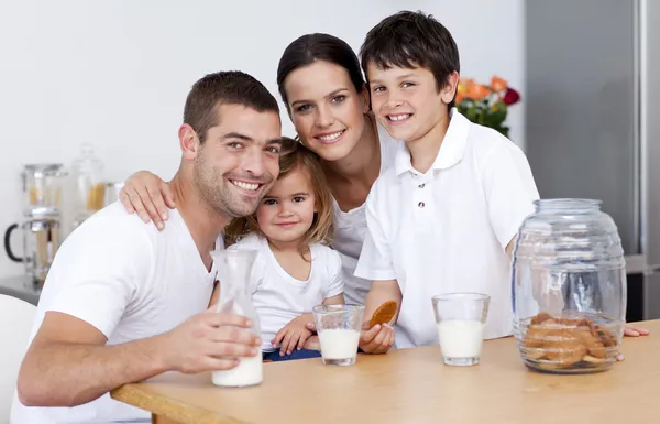 Happy family eating biscuits and drinking milk