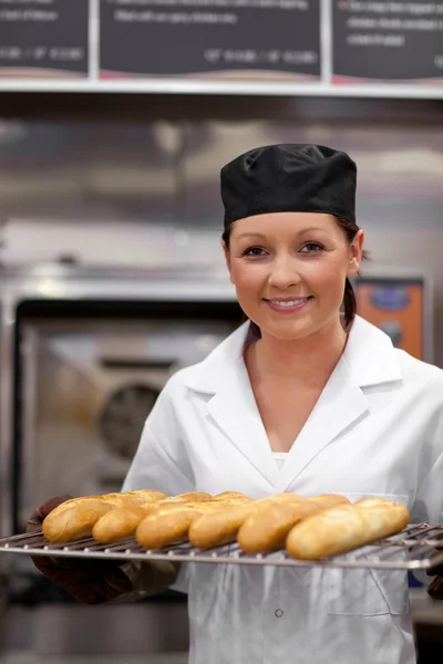 Pretty young baker with baguettes