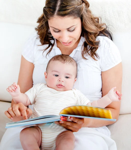 Loving mother reading a story to her adorable baby sitting on th