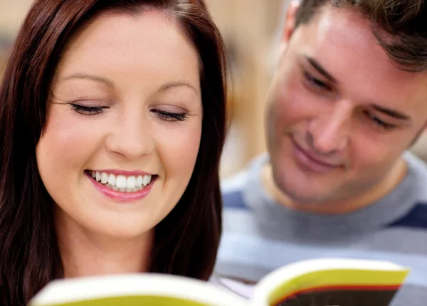 Close-up of a smiling couple of students reading a book