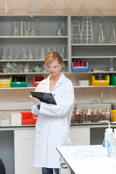 Concentrated female scientist writing on her clipboard