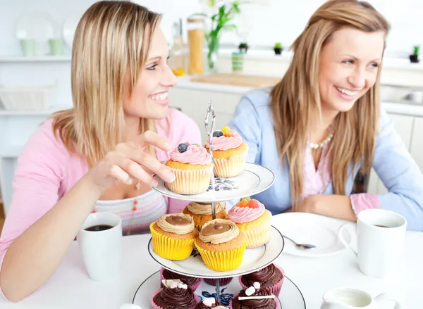 Women having fun eating cupcakes in the kitchen