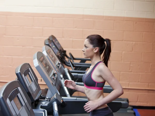 Stock Photo: Serious female athlete doing exercises on treadmill in fitne