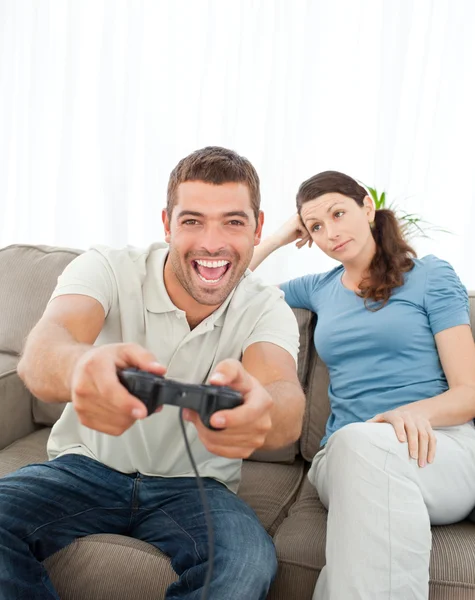 Bored woman looking at her boyfriend playing video game on the s