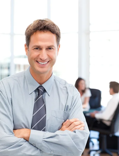 Happy businessman standing in front of his team while working at