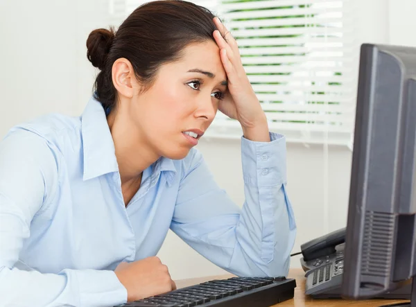 Attractive upset woman looking at a computer screen while sittin